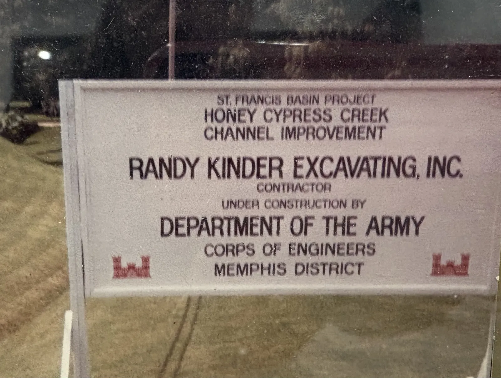 Original project sign reading Randy Kinder Excavating, Inc., contractor for the St. Francis Basin Project, Honey Cypress Creek Channel Improvement, U.S. Army Corps of Engineers, Memphis District
