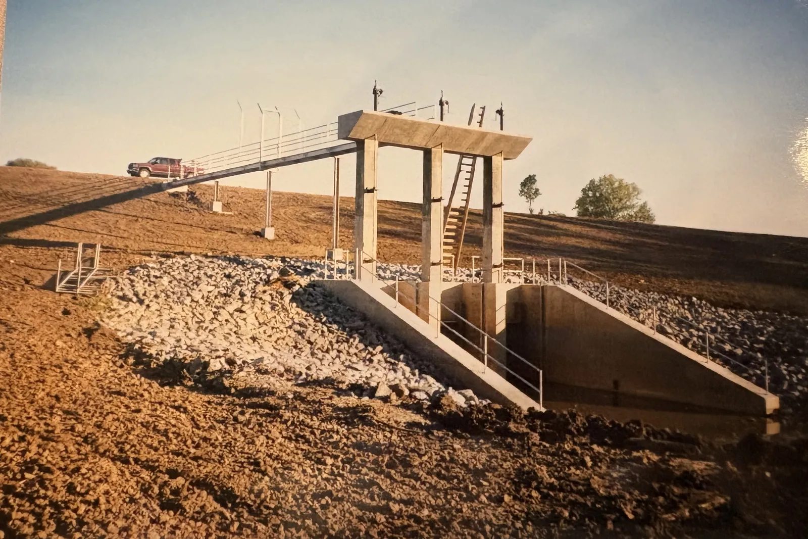 A completed concrete outlet structure with access catwalk on an RKE detention basin