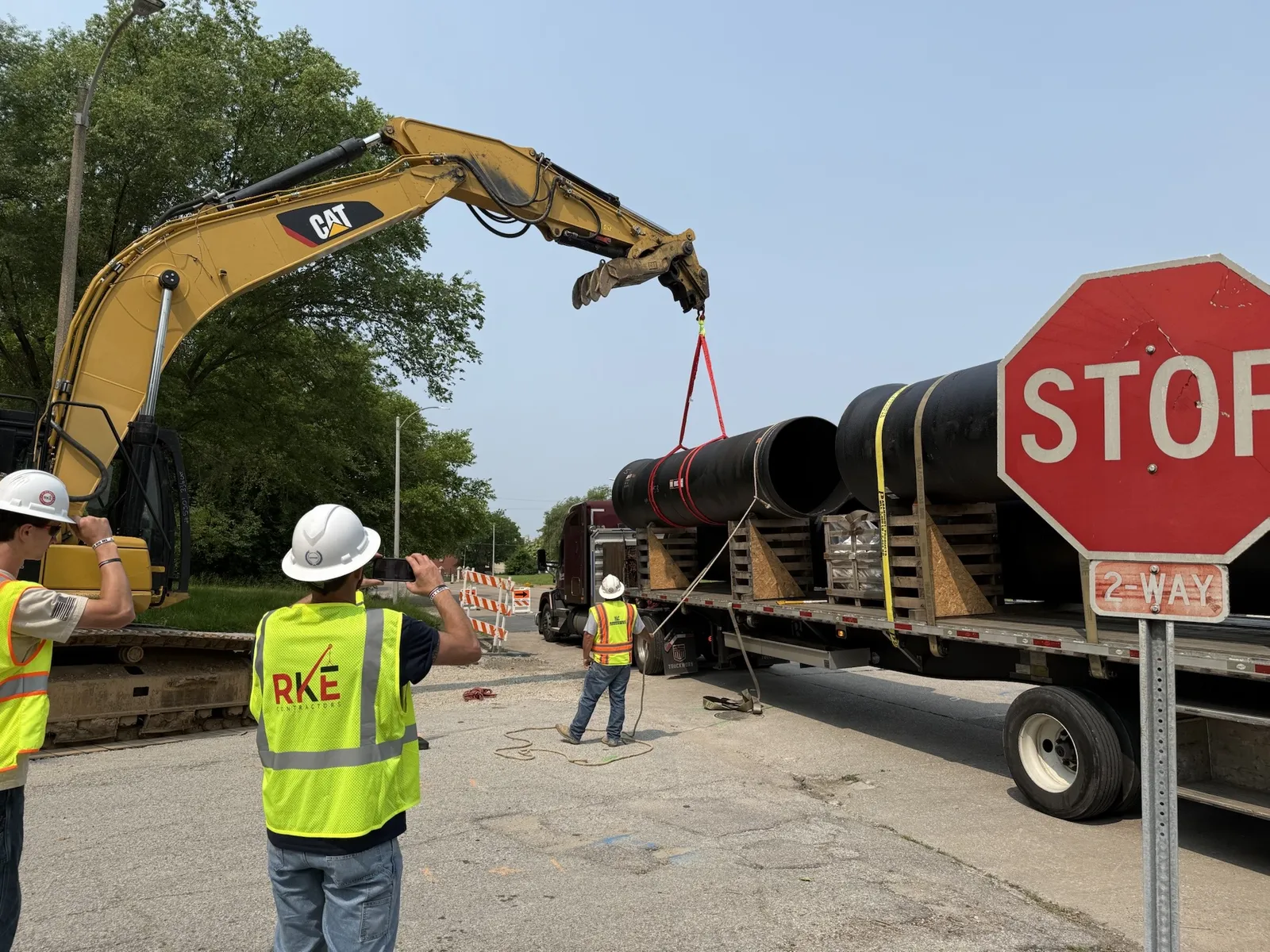 RKE crew and excavator loading pipe on a job site